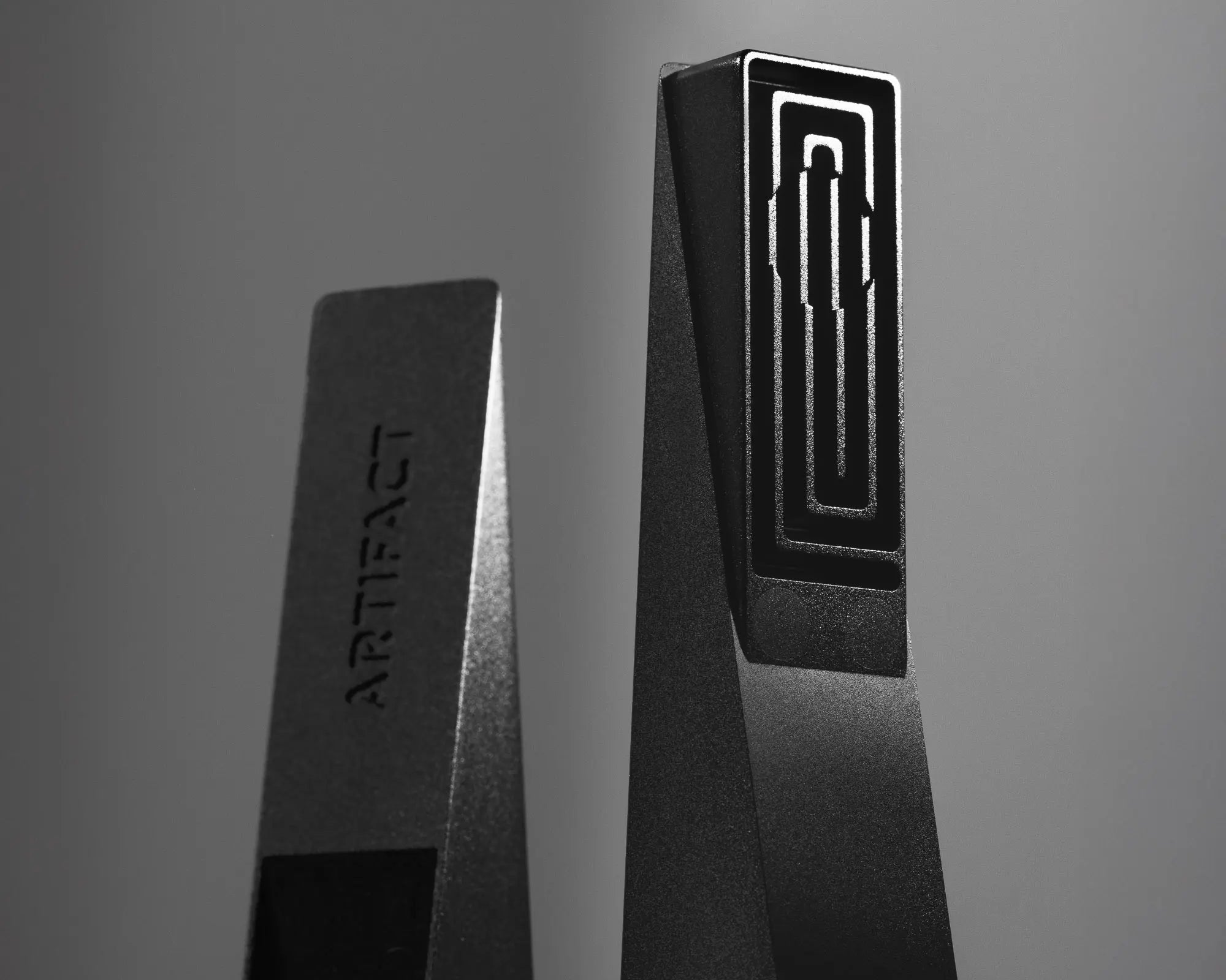 Two black rectangular objects with 'ARTIFACT' branding on a gray background