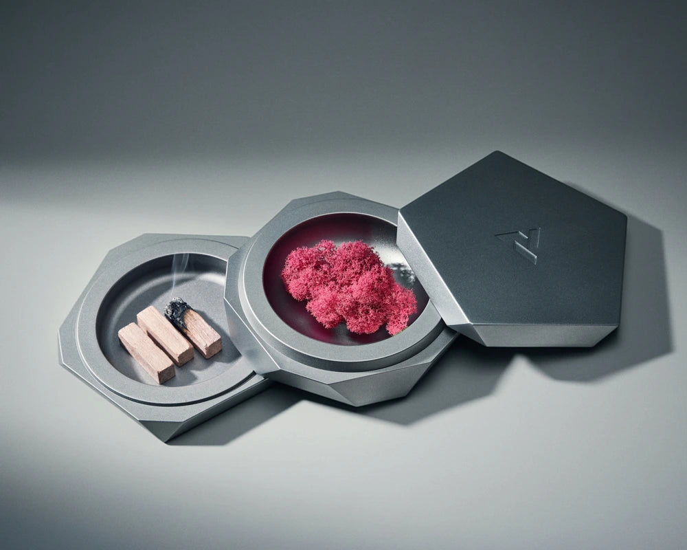 Metallic container with pink substance and small items on a gray background