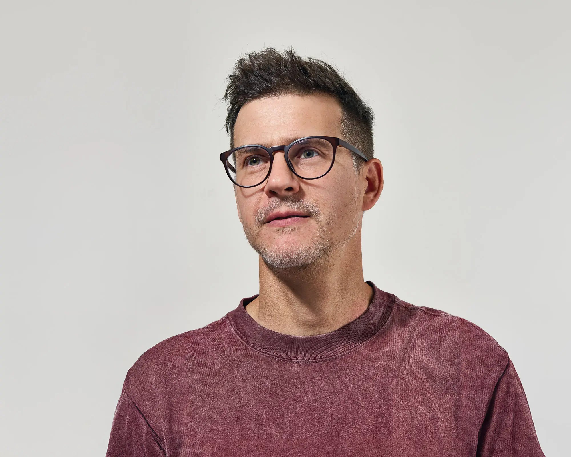 Artifact Founder Ryan Rickett wearing glasses and a maroon shirt against a light gray background