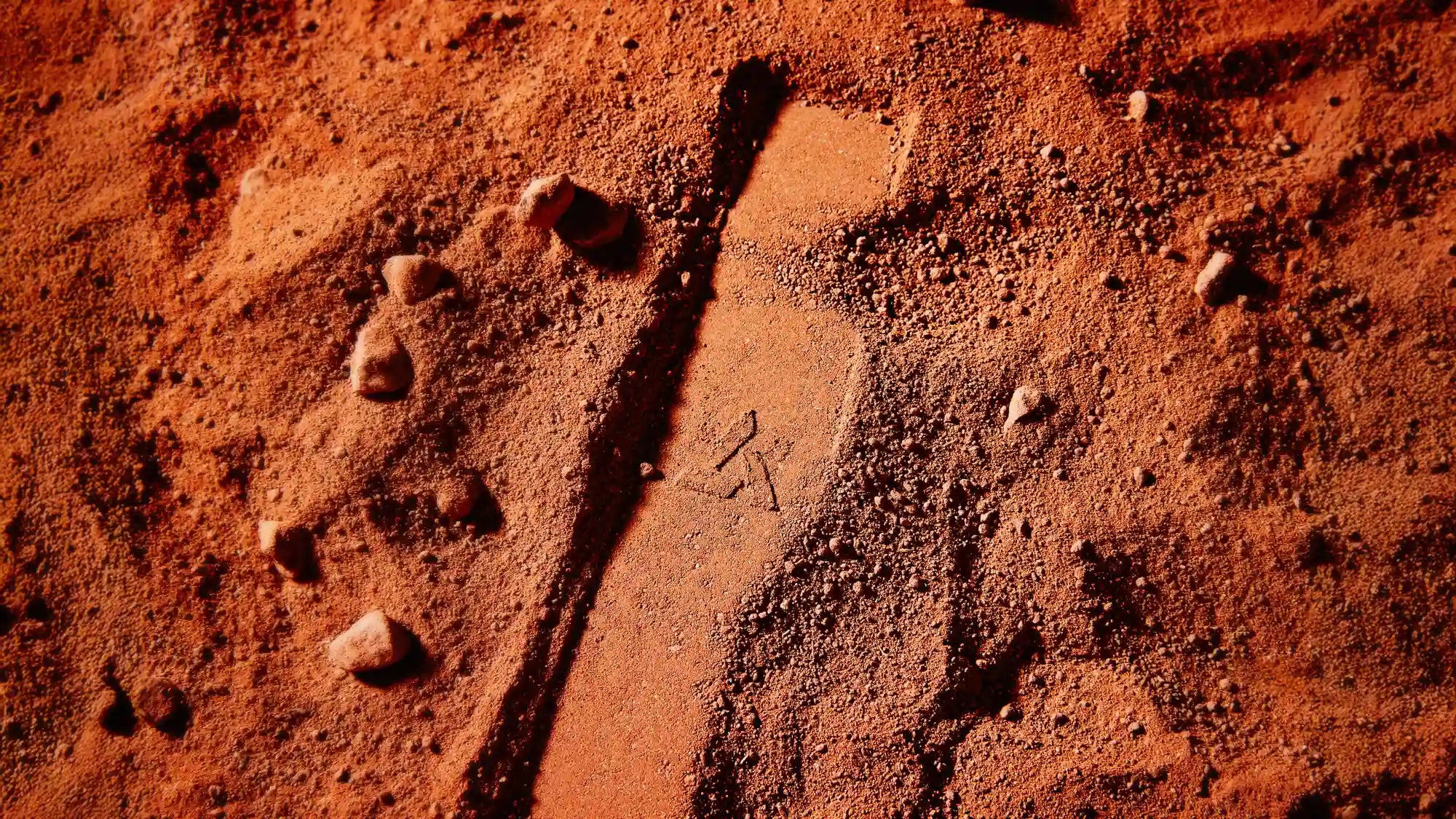 An impression in red sand of the Tempest profile and Artifact logo