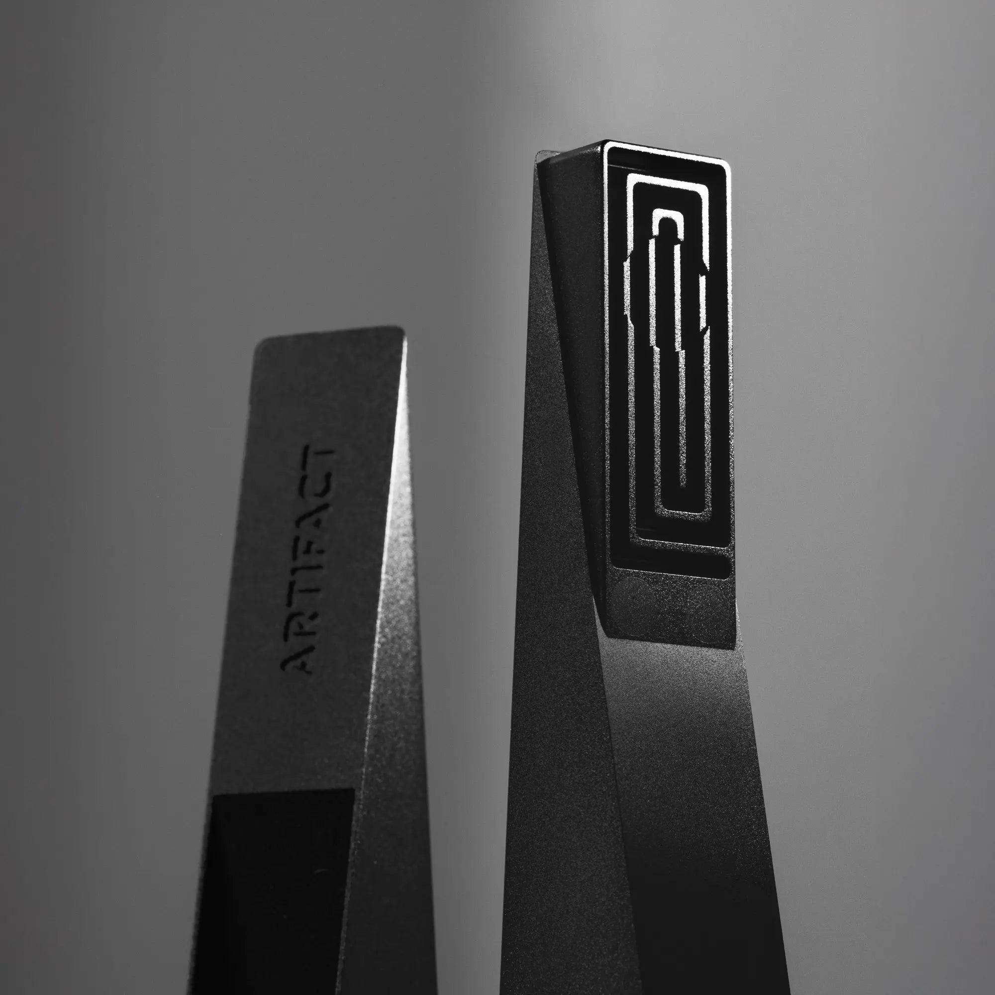 Two black rectangular objects with 'ARTIFACT' branding on a gray background