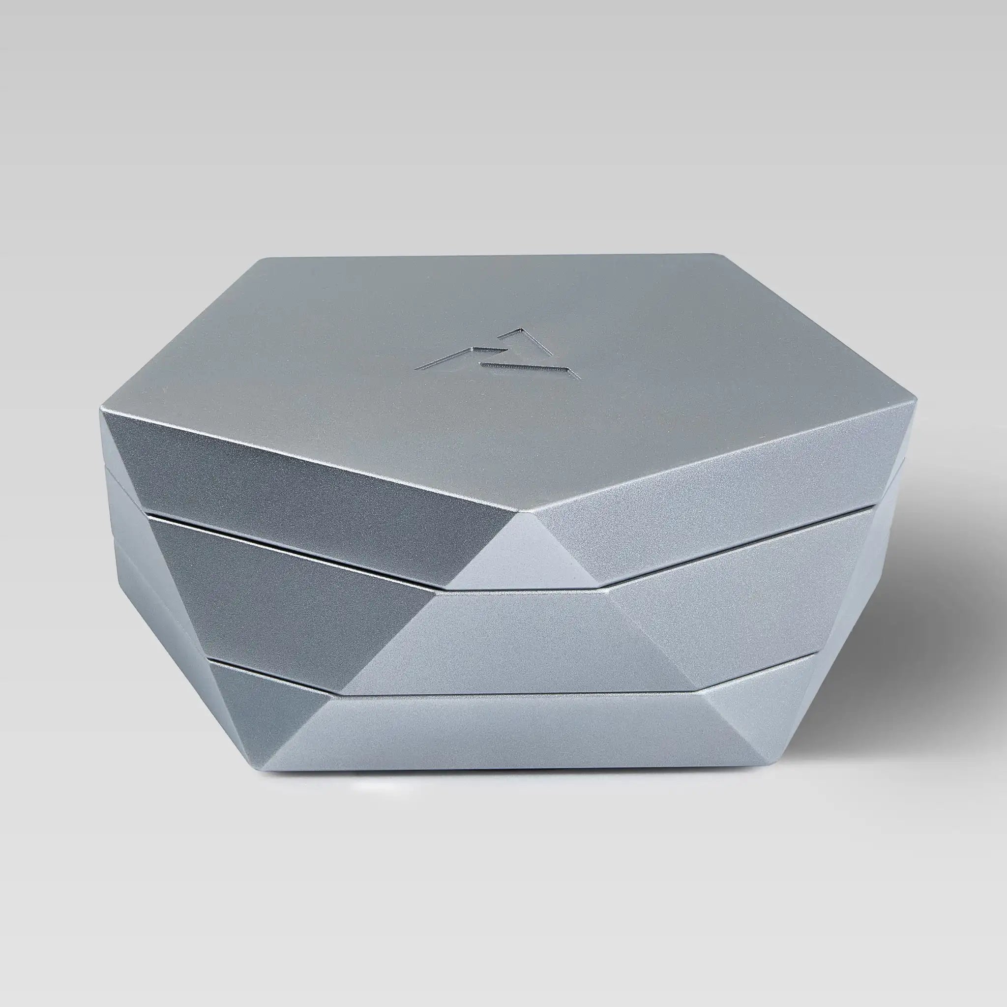 Vesta silver magnetic vessel closed, faceted hexagonal form on a light studio background