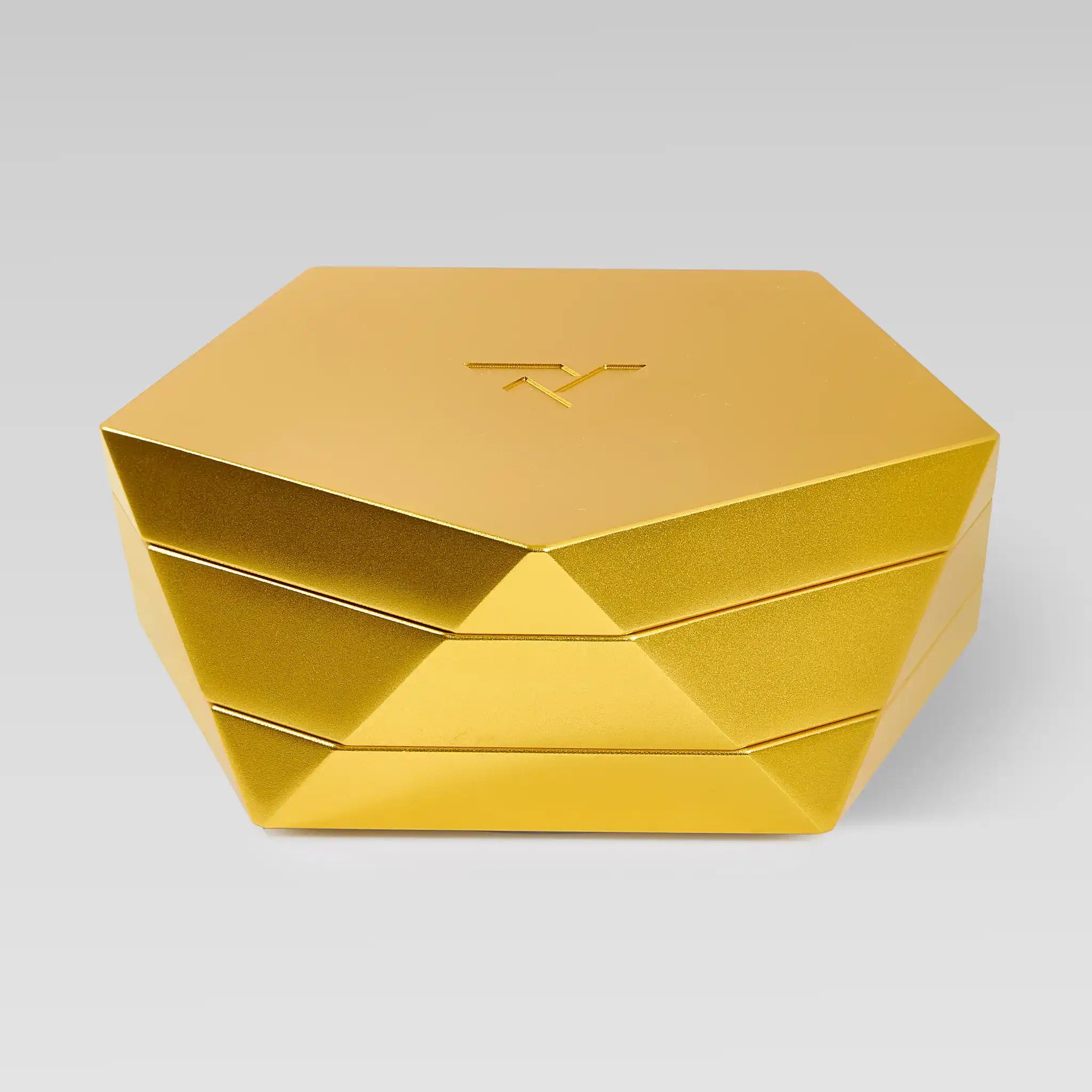 Vesta gold magnetic vessel closed, faceted hexagonal form on a light studio background